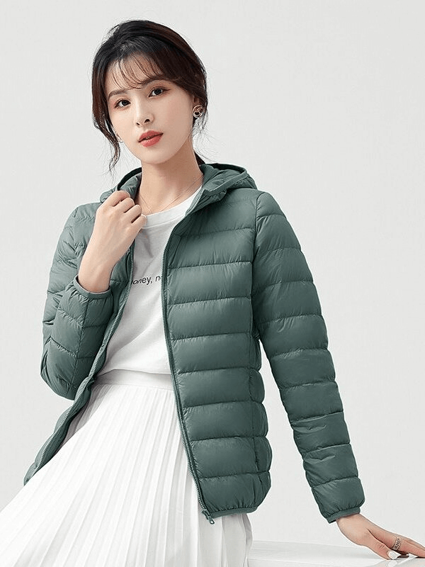 Woman wearing stylish green down jacket with hood, perfect for outdoor warmth, breathable and ultralight design for comfort.